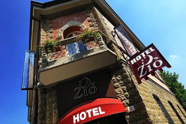Facciata di un hotel con insegne "Hotel Zio" su edificio in pietra e mattoni.